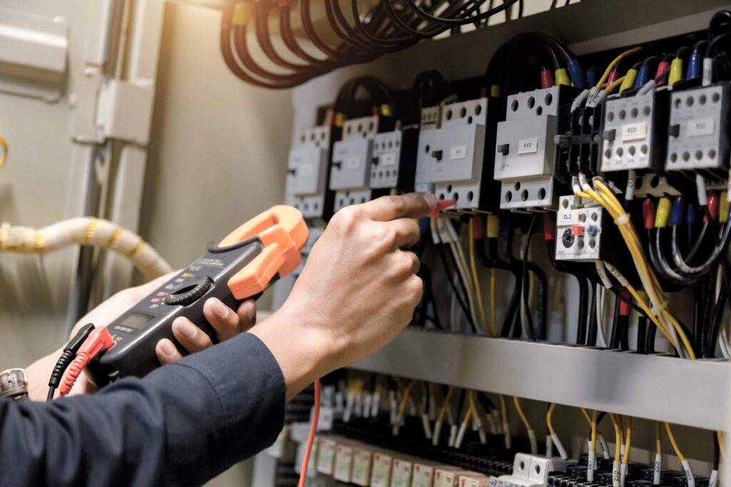 Electrician checking circuit breaker and electrical connections during maintenance in Dubai.