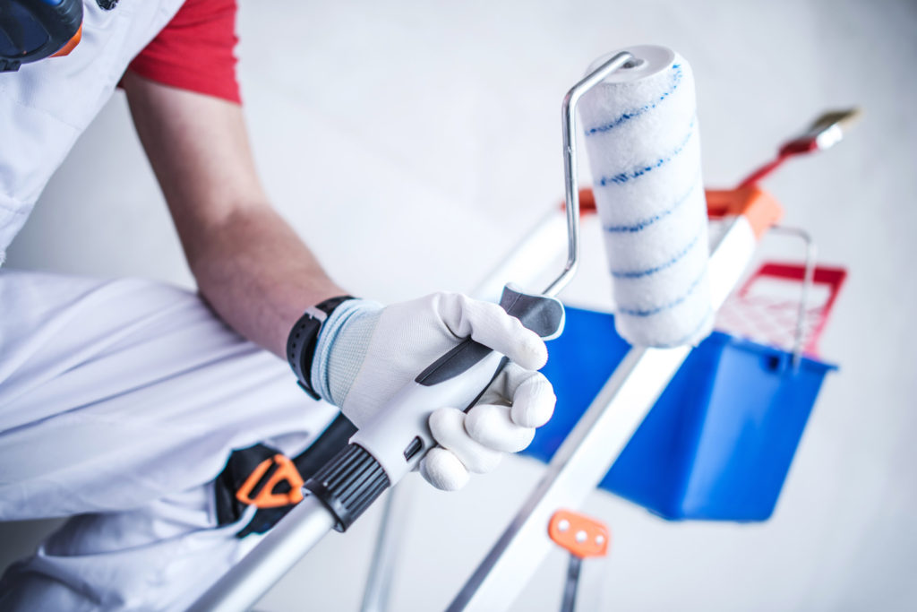 Room Painting Job. Painting Roller in Hand of Worker.