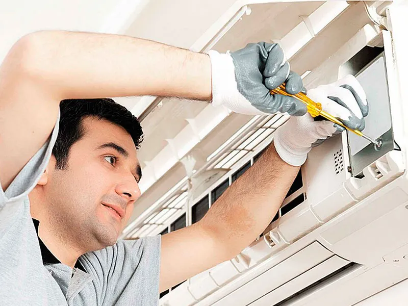 Technicians inspecting air conditioner during AC service in Dubai office